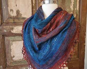 May include: A blue and red knitted shawl with a crocheted border. The shawl is draped over a white mannequin.