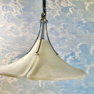 Könnte beinhalten: Eine weiße, blumenförmige Pendelleuchte mit einem verchromten Metallrahmen. Die Leuchte hat ein modernes Design und hängt von der Decke.