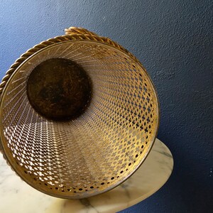 May include: Gold metal umbrella stand with a rope handle and a decorative, perforated design.