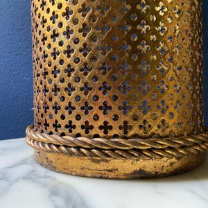 May include: Gold metal lampshade with a decorative, intricate pattern and a rope-like trim around the bottom edge.
