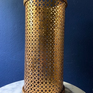 May include: Gold metal umbrella stand with a decorative rope trim and a perforated design.