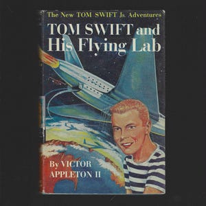 May include: Vintage book cover for "Tom Swift and His Flying Lab." The cover features a retro illustration of a futuristic aircraft, a smiling young man in a striped shirt, and the book's title and author.
