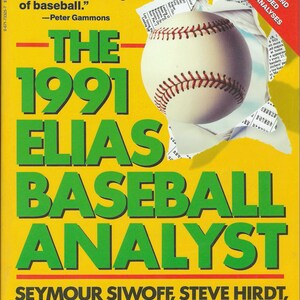May include: A yellow book cover with a green title "The 1991 Elias Baseball Analyst" and a baseball peeking through a torn section of the cover. The book is by Seymour Siwoff, Steve Hirdt, Tom Hirdt, and Peter Hirdt. It features a special section on Maris & Mantle's '61 Yankees.