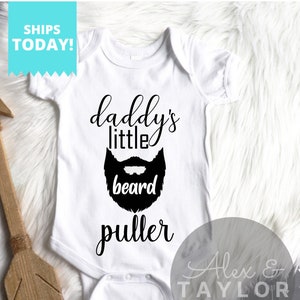 May include: White baby onesie with black text that reads "Daddy's little beard puller" and a black silhouette of a beard.