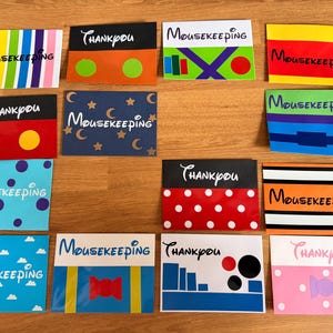 May include: A collection of fourteen rectangular cards featuring various colourful patterns and designs. Each card displays the text Mousekeeping or Thankyou in a stylised font. The designs include stripes, polka dots, clouds, and geometric shapes.