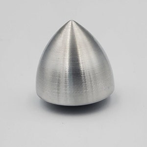 Puede incluir: Una peonza de metal plateado con una punta puntiaguda y un acabado liso y cepillado.