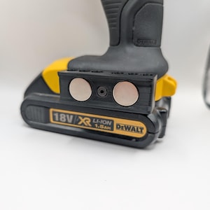 May include: A black and yellow DeWalt 18V XR 1.5Ah battery pack with a black accessory attached. The accessory has two silver circular magnets. The drill is black and yellow.