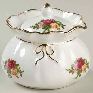 以下が含まれることがあります： 赤、黄、緑のバラの花柄が施された、蓋付きの白い磁器製の砂糖入れ。袋の形をしたボウルで、金色のリボンと上部に金色の縁取りが施されています。