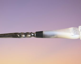 May include: A silver letter opener with a white pearl handle. The handle is carved with a floral design.