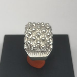 Peut inclure: Une bague en argent avec un motif textur&eacute; de petites bosses rondes. La bague est de forme rectangulaire et a une finition lisse et polie.