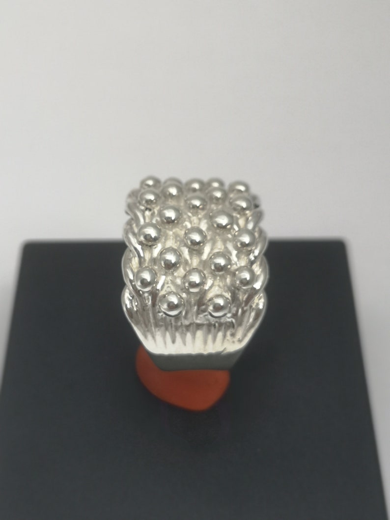 Peut inclure: Une bague en argent avec un motif textur&eacute; de petites bosses rondes. La bague est de forme rectangulaire et a une finition lisse et polie.