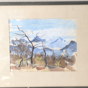 May include: A framed watercolour painting depicting a landscape with a mountain range in the background. The foreground features a group of trees with bare branches, set against a blue sky with white clouds.