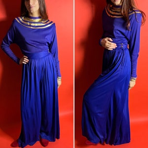 May include: A two-piece outfit in a deep blue color with gold trim. The top has a high neckline and long sleeves. The pants are wide-legged and flowy.