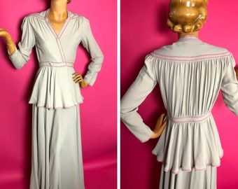 May include: A long, gray dress with a wrap-style bodice and a tiered skirt. The dress has pink stitching around the neckline, waist, and hem.