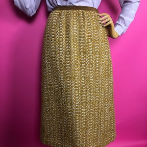 May include: A brown and white tweed skirt with a brown waistband. The skirt is knee-length and has a straight silhouette.
