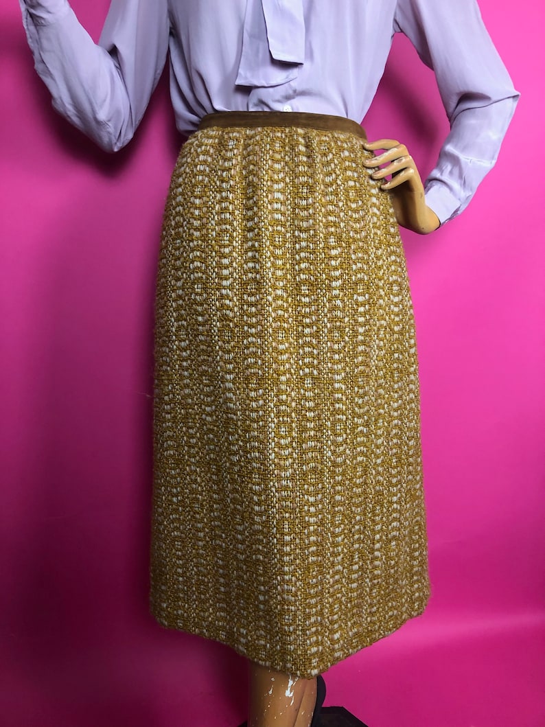 May include: A brown and white tweed skirt with a brown waistband. The skirt is knee-length and has a straight silhouette.