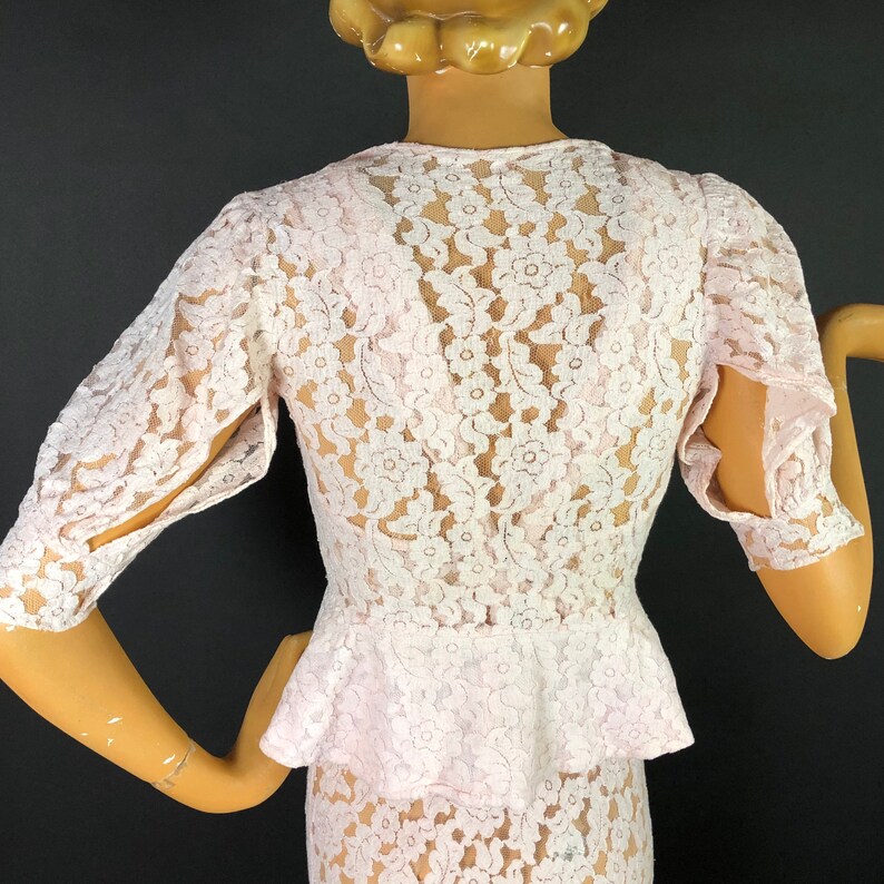 May include: A white lace dress with a fitted bodice and a ruffled skirt. The dress has a scoop neckline and short sleeves.