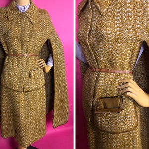 May include: A brown and white tweed cape with a brown leather belt and a small pocket on the front. The cape has a long, flowing design and is perfect for a vintage look.