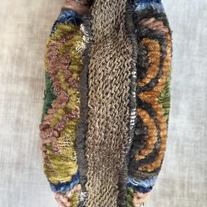 May include: A small, colorful, rectangular pouch with a brown fabric strap. The pouch is made of a variety of fabrics, including velvet, and has a patchwork design.