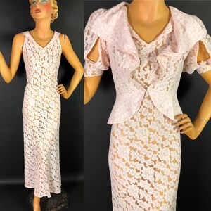 May include: A pink lace dress with a ruffled neckline and short sleeves. The dress is sheer and has a floral pattern.