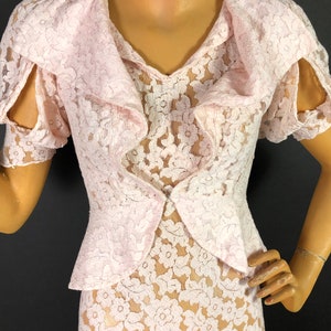 May include: A pink lace dress with a ruffled collar and short sleeves. The dress has a fitted bodice and a flowing skirt.