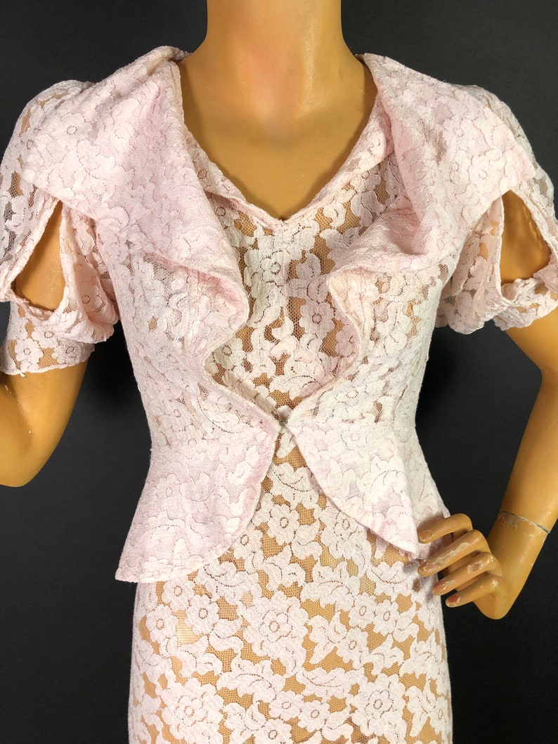 May include: A pink lace dress with a ruffled collar and short sleeves. The dress has a fitted bodice and a flowing skirt.