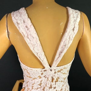 May include: A pink lace top with a V-shaped back and a criss-cross design in the back.
