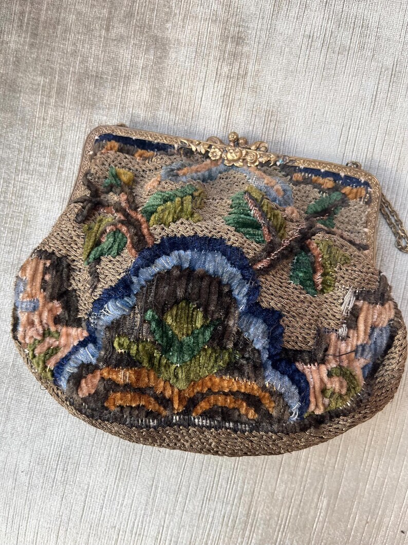 May include: A vintage embroidered purse with a gold metal clasp and chain. The purse is made of a brown fabric with colorful floral embroidery.