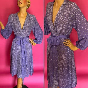 May include: A purple wrap dress with white polka dots and a matching sash. The dress has long sleeves with a gathered cuff and a V-neckline.
