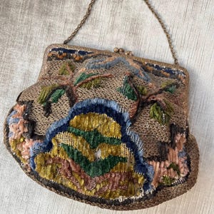 May include: A vintage embroidered purse with a chain strap. The purse is made of a brown fabric with colorful embroidery, including green, blue, yellow, and pink.