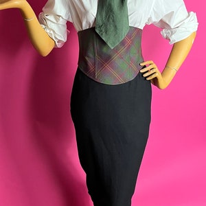May include: A white button-down shirt with a green tie, a plaid corset, and a black pencil skirt.