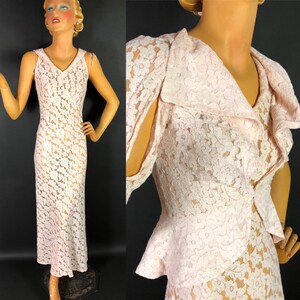 May include: A delicate pink lace dress with a ruffled collar and a fitted bodice. The dress has a sleeveless design and a flowing skirt.