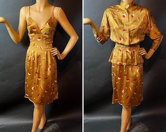 May include: Two vintage gold-colored outfits on mannequins. One is a slip dress with spaghetti straps. The other is a two-piece set with a button-up blouse and a skirt. Both outfits feature a repeating pattern of red, white, and brown shapes.
