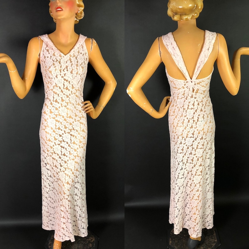 May include: A white lace maxi dress with a V-neckline and a sleeveless design. The dress has a floral pattern and is sheer.