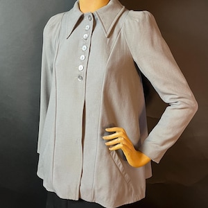 May include: A grey long-sleeved collared jacket with a button-up front and a single pocket on the left side.