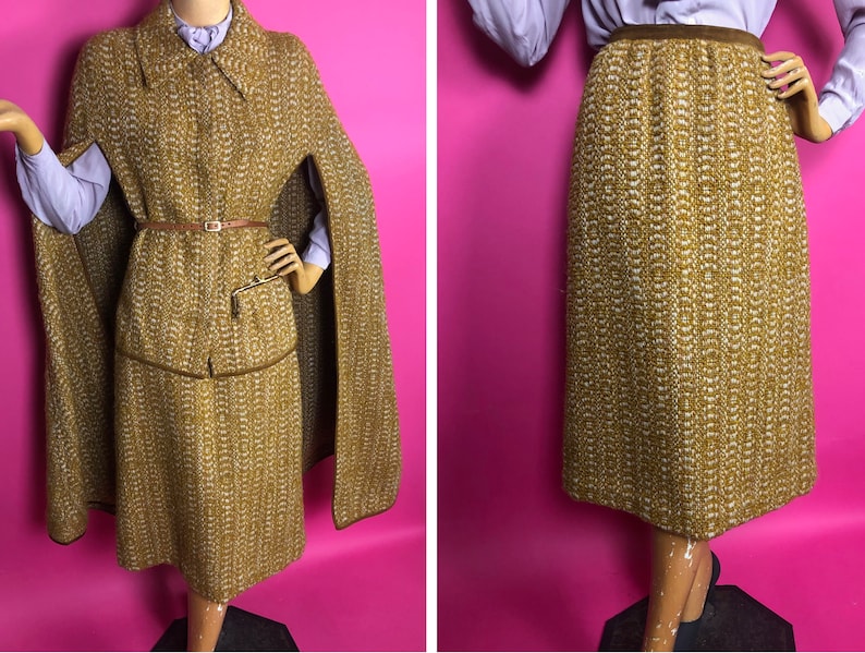 May include: A brown and white tweed skirt and matching cape with a brown leather belt. The skirt is knee-length and the cape has a collar.