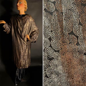 May include: A long, black coat with a gold and silver brocade pattern. The fabric has a raised texture and a subtle sheen.