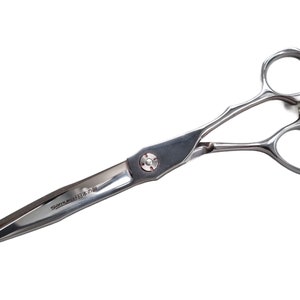 Może przedstawiać: Srebrne nożyczki fryzjerskie z zakrzywionym uchwytem i ostrym ostrzem. Nożyczki mają małą czerwoną kropkę na uchwycie, a na ostrzu wygrawerowany jest napis "SUMI-JAPAN".