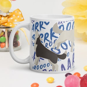 May include: White ceramic mug with a blue and white design featuring two cartoon wolves howling with the words "AROOO" and "ARRR" repeated around them.