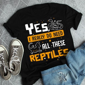 Könnte beinhalten: Schwarzes T-Shirt mit einer gelben Grafik, auf der "YES, I REALLY DO NEED ALL THESE REPTILES" steht. Die Grafik enthält auch eine Schlange und ein Eidechse.