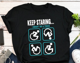 May include: Black t-shirt with the text "KEEP STARING... I MIGHT DO A TRICK" and four white icons on a teal background. The icons depict a person in a wheelchair performing different actions.