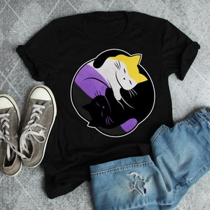 May include: Black t-shirt with a yin yang symbol design featuring a black cat and a white cat with yellow accents. The symbol is purple, yellow, and black.