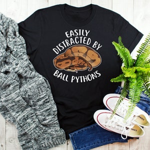 Könnte beinhalten: Schwarzes T-Shirt mit einem weißen Aufdruck eines Königspythons und dem Text "Leicht abgelenkt von Königspythons".