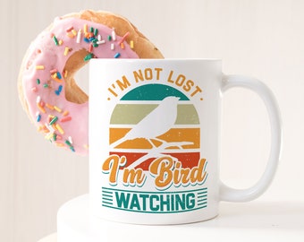 May include: White ceramic mug with a retro-style design featuring a bird silhouette and the text "I'm not lost, I'm bird watching".