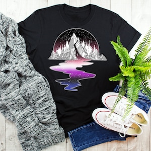 Könnte beinhalten: Schwarzes T-Shirt mit einem Motiv einer Bergkette, die sich in einem See mit einer galaktischen Reflexion spiegelt. Das Motiv ist in Schwarzweiß mit einer lila, rosa und blauen Galaxie-Reflexion gehalten.
