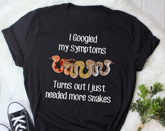 Puede incluir: Camiseta negra con un gráfico blanco de serpientes y el texto "Busqué mis síntomas en Google Resulta que solo necesitaba más serpientes."