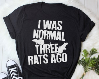 May include: Black t-shirt with white text that reads "I was normal three rats ago". The text is distressed and there are three rat silhouettes on the shirt.