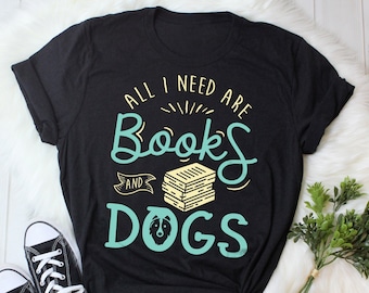 May include: Black t-shirt with the text "All I need are books and dogs" in teal blue lettering. A stack of books and a dog silhouette are featured in the design.