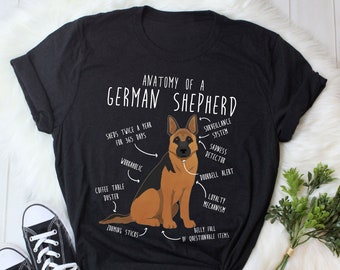 May include: A black t-shirt with a white graphic of a German Shepherd dog. The graphic includes text that says "Anatomy of a German Shepherd" and lists various dog traits, such as "Surveillance System", "Sadness Detector", and "Loyalty Mechanism".