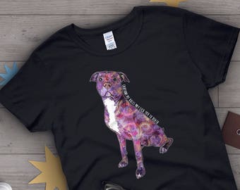 Op de afbeelding: Zwart T-shirt met een afbeelding van een paarse en witte pit bull. De hond draagt een galaxy print en de tekst "LET OP: PITBULLS KUNNEN JE DOOD LIKKEN" staat op het shirt.
